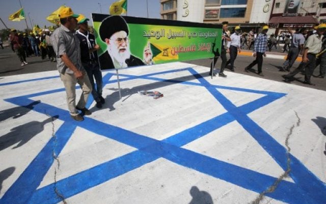 Illustrative: Iraqi men stand on an Israeli flag and hold a banner depicting Iran's Supreme Leader Ayatollah Ali Khamenei as they take part in a parade marking al-Quds (Jerusalem) Day in Baghdad, July 1, 2016. (AFP Photo/Ahmad Al-Rubaye) Illustrative: Iraqi men stand on an Israeli flag and hold a banner depicting Iran's Supreme Leader Ayatollah Ali Khamenei as they take part in a parade marking al-Quds (Jerusalem) Day in Baghdad, July 1, 2016. (AFP Photo/Ahmad Al-Rubaye)