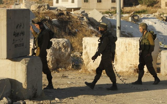 Illustrative: IDF soldiers carry spike strips as they block a road at a southern entrance of Hebron on July 2, 2016, after Israeli troops locked down the West Bank city following a spate of deadly Palestinian terror attacks. (AFP/Hazem Bader/File) Illustrative: IDF soldiers carry spike strips as they block a road at a southern entrance of Hebron on July 2, 2016, after Israeli troops locked down the West Bank city following a spate of deadly Palestinian terror attacks. (AFP/Hazem Bader/File)