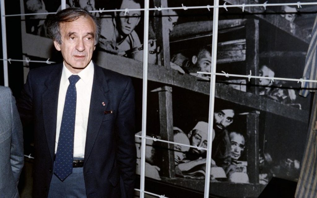 Elie Wiesel stands in front of a photo of himself (bottom row, third from right) and other inmates, taken at the Buchenwald concentration camp in 1945, during his visit to the Yad Vashem Holocaust Memorial and Museum in Jerusalem, December 18, 1986. (AFP/ SVEN NACKSTRAND)