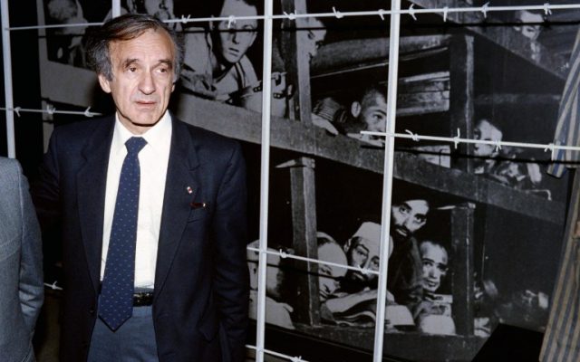 Elie Wiesel stands in front of a photo of himself (bottom row, third from right) and other inmates, taken at the Buchenwald concentration camp in 1945, during his visit to the Yad Vashem Holocaust Memorial and Museum in Jerusalem, December 18, 1986. (AFP/ SVEN NACKSTRAND)