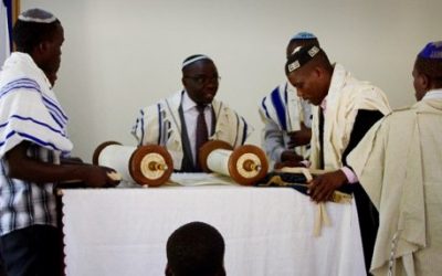 Rabbi Gershom Sizomu, second left, prepares to read the Torah during a Shabbat service among the Abayudaya Jewish community, in a village near Mbale, eastern Uganda, July 2, 2016. (AFP/Michael O'Hagan)