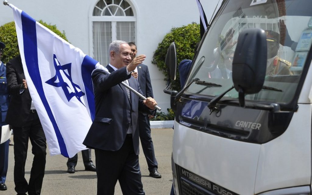 Prime Minister Benjamin Netanyahu holds an Israeli national flag after a join press conference with and Kenya's President in July 5, 2016 at the State House, in Nairobi. (AFP PHOTO/SIMON MAINA)