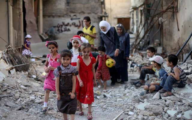 Syrian children walk amidst destruction during an activity organised by a charity group in Jobar, a rebel-held district on the eastern outskirts of the capital Damascus, ahead of Eid al-Fitr holyday in the war-torn country on July 5, 2016. (AFP PHOTO / AMER ALMOHIBANY)