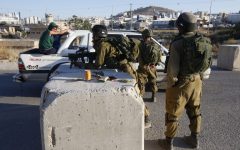 Israeli soldiers check a car as they block vehicles from crossing from the West Bank city of Hebron to the town of Yatta on July 6, 2016. (AFP/HAZEM BADER)