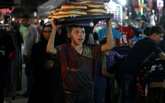 A Syrian boy sells bread at a market in the rebel-held area of the northern Syrian city of Aleppo on July 5, 2016 as Syrians shop on the eve of Eid al-Fitr which marks the end of the Muslim holy fasting month. (AFP PHOTO / THAER MOHAMMED)