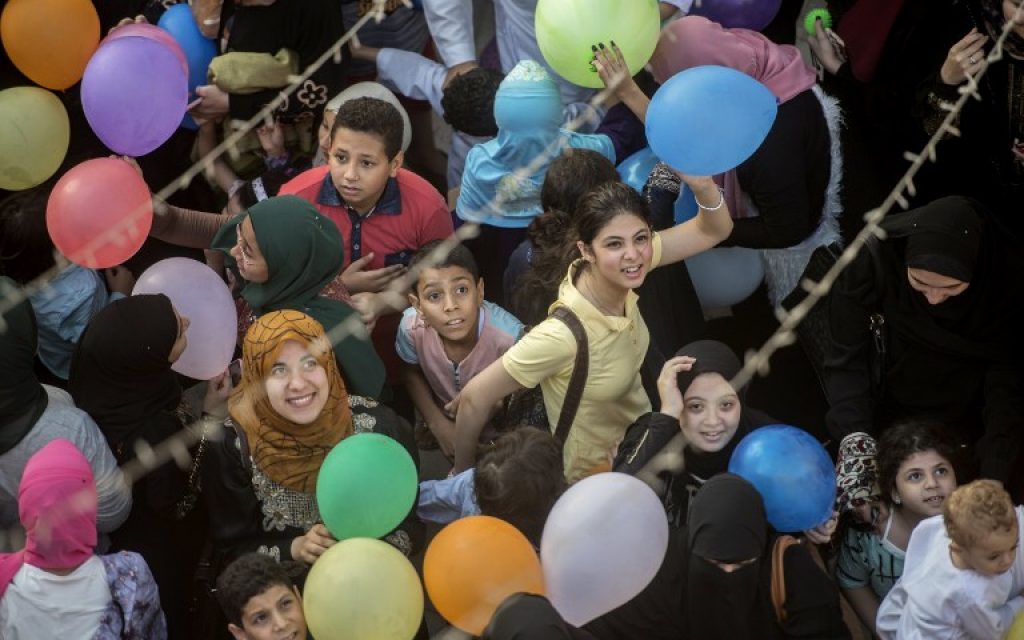 Egyptian Muslims worshippers look up as balloons are released from the roof top of a mosque at the end of prayers on the first day of Eid al-Fitr holiday on July 6, 2016 in the Nile Delta city of Mansura, some 120 kms north of Cairo. (AFP PHOTO / KHALED DESOUKI)