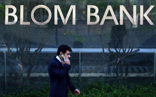 This file photo taken on June 13, 2016 shows a man walking past the sign of the BLOM BANK in the Lebanese capital Beirut. (AFP PHOTO / PATRICK BAZ) This file photo taken on June 13, 2016 shows a man walking past the sign of the BLOM BANK in the Lebanese capital Beirut. (AFP PHOTO / PATRICK BAZ)