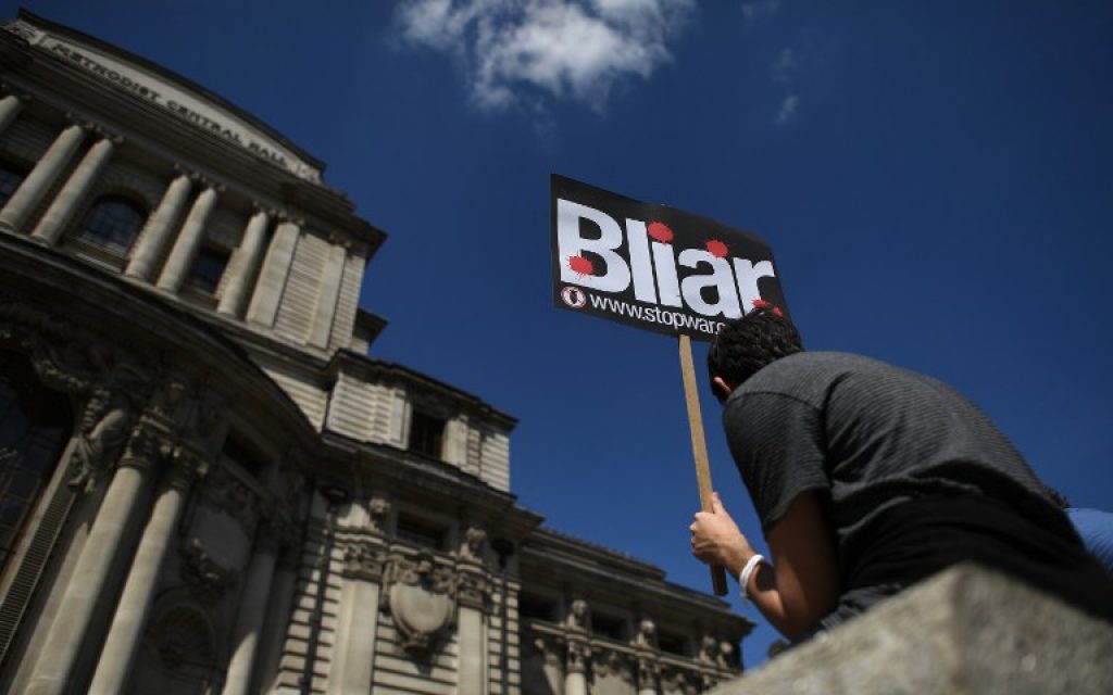 A demonstrator holds a placard during a protest near the venue of the publication of the Iraq Inquiry report in London on July 6, 2016. (AFP/BEN STANSALL)