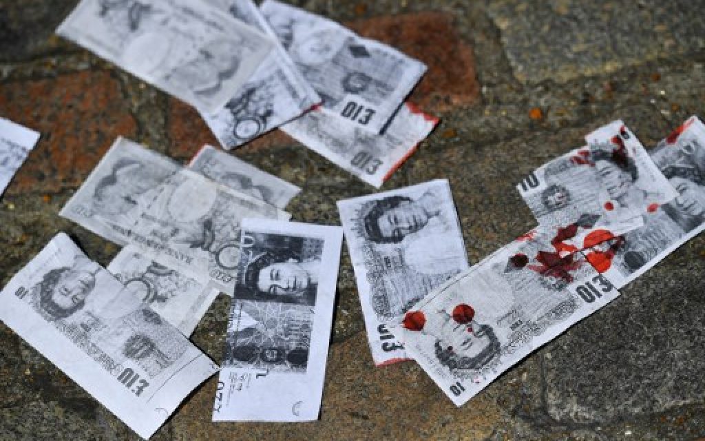 Fake money, stained red to symbol spilled blood, is pictured on the floor following a protest by anti-war demonstrators outside QEII Centre in London on July 6, 2016, as they wait to hear the outcome of the Iraq Inquiry report. (AFP PHOTO / BEN STANSALL)