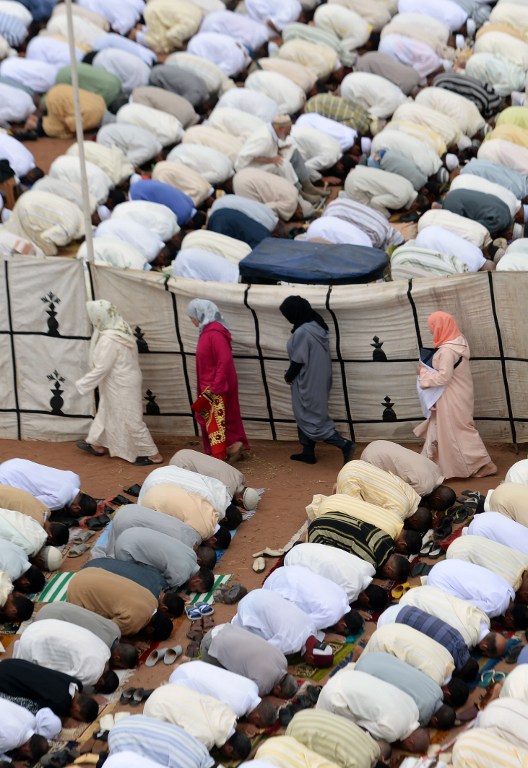 Moroccan women walks as Muslim men perform prayers for Eid al-Fitr which marks the end of the Muslim holy fasting month of Ramadan in the city of Sale, north of the Moroccan capital Rabat on July 6, 2016. (AFP PHOTO / FADEL SENNA)