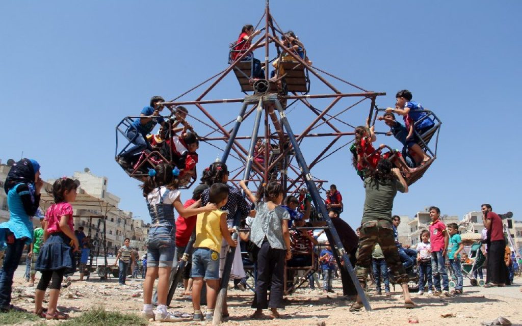 Syrian children ride on an attraction as they celebrate Eid al-Fitr, which marks the end of the Muslim holy fasting month of Ramadan, in Syria's rebel-held northwestern city of Idlib on July 6, 2016. (AFP PHOTO / Omar haj kadour)