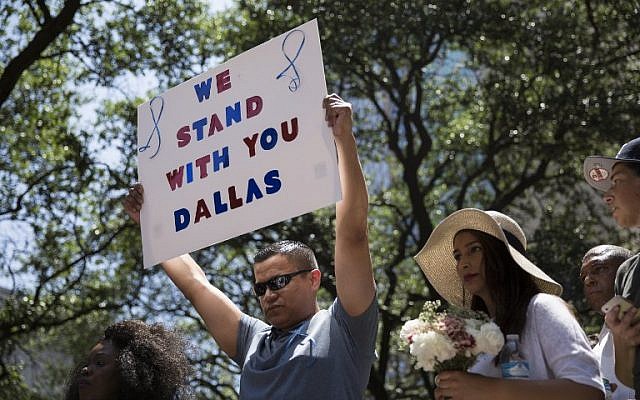A man holds a sign reading 'We Stand With You Dallas' during a vigil at Thanks-Giving Square in Dallas, Texas, on July 8, 2016, following the shootings during a peaceful protest on July 7 that left 5 police officers dead. (AFP PHOTO/Laura Buckman) A man holds a sign reading 'We Stand With You Dallas' during a vigil at Thanks-Giving Square in Dallas, Texas, on July 8, 2016, following the shootings during a peaceful protest on July 7 that left 5 police officers dead. (AFP PHOTO/Laura Buckman)