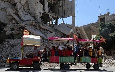 Syrian children enjoy a tour on a makeshift miniature train during the celebrations marking the end of the Muslim month of Ramadan on July 9, 2016 in Syrian the rebel-held town of Arbin in the eastern Ghouta region on the outskirts of the capital Damascus. (AFP PHOTO/AMER ALMOHIBANY)