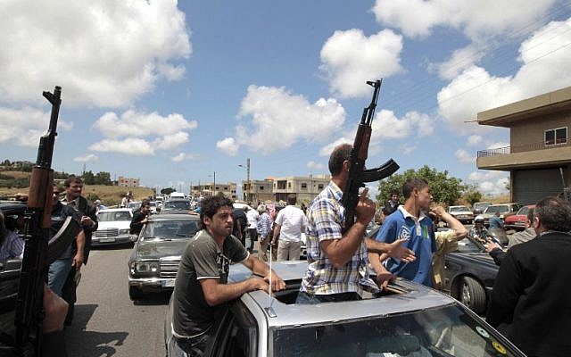 Armed Sunni Muslim men brandishing their weapons as they escort the ambulance carrying the body of Sheikh Ahmad Abdel Wahed, who was shot by army troops when his convoy failed to stop at a checkpoint as they arrive at the entrance of his hometown al-Bireh, north of Beirut, for his funeral. May 21, 2012 (AFP PHOTO / JOSEPH EID)