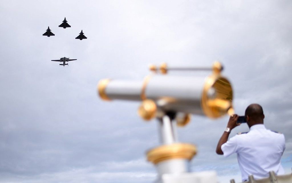 A man takes a picture as three Rafale M fighter jets fly ahead of an E2C during the annual Bastille Day military parade on the Champs-Elysees avenue in Paris on July 14, 2016. (AFP/ STEPHANE DE SAKUTIN)