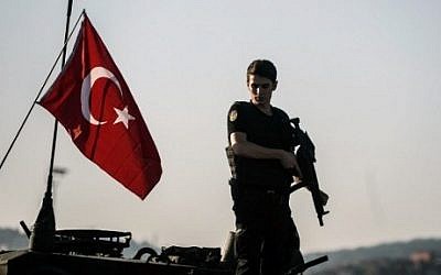 A Turkish anti-riot police officer stands guard on a tank after a military position on the Bosphorus bridge was taken over in Istanbul on July 16, 2016. (AFP Photo/Ozan Kose)
