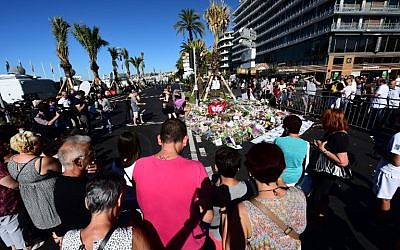 People lay flowers, candles and messages at a makeshift memorial in Nice on July 16, 2016, in tribute to the victims of the Bastille Day attack on the Promenade des Anglais seafront which killed 84 people. (AFP PHOTO/GIUSEPPE CACACE)