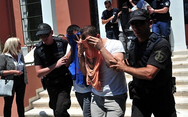 Turkish officers escorted by Greek police officers leave the courthouse of Alexandroupoli after appearing before a Greek prosecutor, on July 17, 2016. The eight, who have claimed asylum in Greece, arrived by military helicopter on July 16, 2016 after sending a distress signal to authorities at the airport in northern Alexandroupoli. (AFP/SAKIS MITROLIDIS)