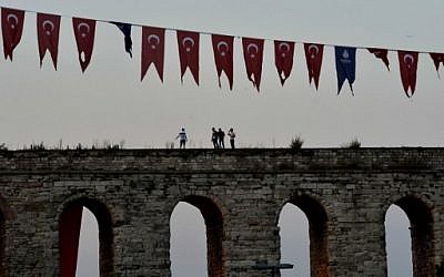 People walk atop a historical wall next to Turkish flags in Istanbul on July 17, 2016. (AFP PHOTO / ARIS MESSINIS) People walk atop a historical wall next to Turkish flags in Istanbul on July 17, 2016. (AFP PHOTO / ARIS MESSINIS)