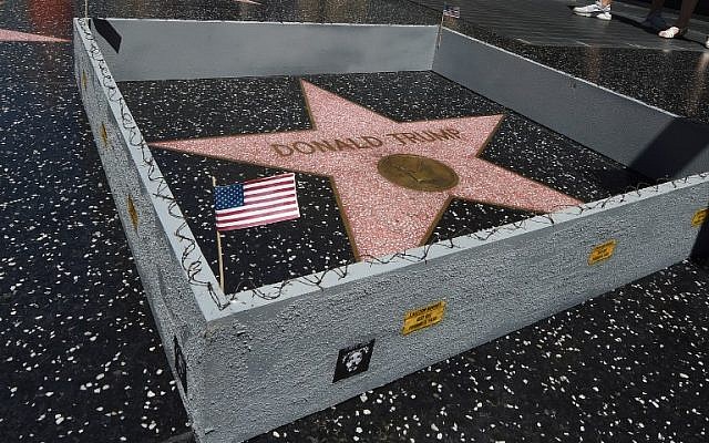 The Hollywood Walk of Fame star of Republican presidential candidate Donald Trump is surrounded by a miniature wall complete with mock razor wire and American flags, placed by street artist Plastic Jesus in Hollywood, California, on July 20, 2016. (AFP/Mark Ralston)