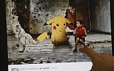 A journalist looks at a montage by a Syrian activist, using the international frenzy over the Pokemon Go game to draw new attention to the battle-scarred country, in Beirut on July 22, 2016. (Joseph Eid)