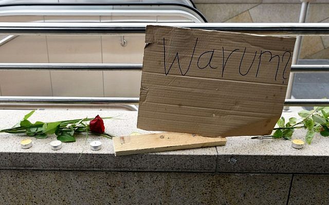 A poster reading 'Why?' rests next to flowers and candles in an impromptu memorial near a shopping mall in Munich on July 23, 2016, a day after a gunman went on a shooting rampage, killing nine people in a suspected terror attack. (AFP PHOTO/Christof Stache)