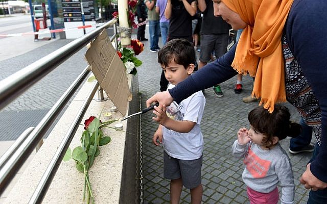 A veiled woman and her children lights candles to commemorate victims at the entrance of the subway station near the shopping mall Olympia Einkaufzentrum OEZ in Munich on July 23, 2016, a day after a gunman went on a shooting rampage, killing nine people in a suspected terror attack. (AFP PHOTO/Christof Stache) A veiled woman and her children lights candles to commemorate victims at the entrance of the subway station near the shopping mall Olympia Einkaufzentrum OEZ in Munich on July 23, 2016, a day after a gunman went on a shooting rampage, killing nine people in a suspected terror attack. (AFP PHOTO/Christof Stache)