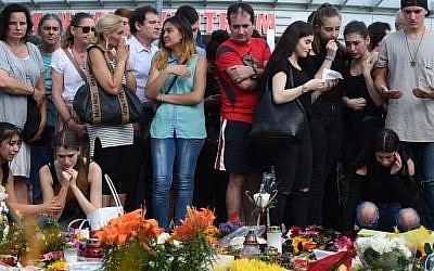 People mourn in front of candles and flowers on July 24, 2016 in front of the Olympia Einkaufszentrum shopping center in Munich, southern Germany, where an 18-year-old German-Iranian student run amok. (AFP / Christof Stache)