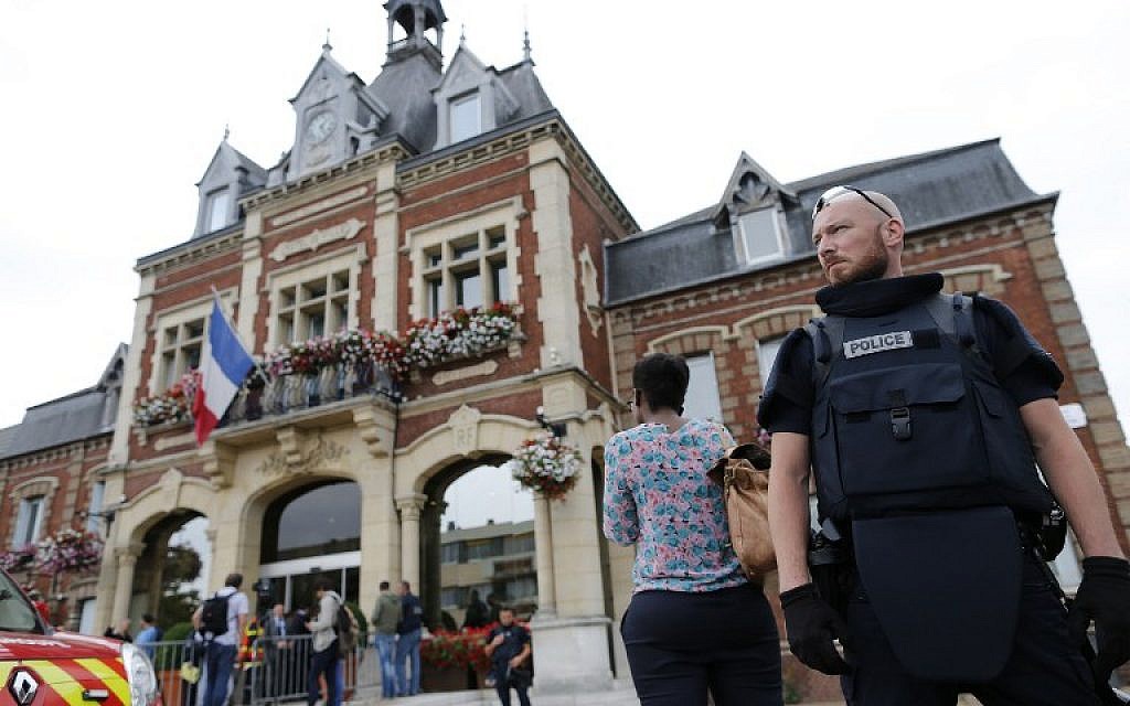 A French police officer stands guard by Saint-Etienne-du-Rouvray's city hall following a hostage-taking at a church in Saint-Etienne-du-Rouvray, northern France, on July 26, 2016 that left the priest dead.(AFP PHOTO / CHARLY TRIBALLEAU)