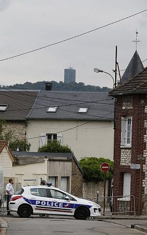 A French police officer stands on guard behind the church of Saint-Etienne-du-Rouvray on July 26, 2016, following an attack by two knife-wielding men that killed an elderly priest. (AFP PHOTO/MATTHIEU ALEXANDRE)
