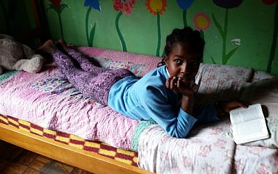 A girl reads the Bible in her bed at the Addis Ababa AHOPE Center for HIV-positive orphans, July 7, 2016 (Raphael Ahren/Times of Israel)