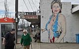 People walk past a mural of US presidential nominee Hillary Clinton clad in a swimsuit, created by street artist Lushsux, in West Footscray, Melbourne on July 30, 2016 (Paul Crock/AFP)