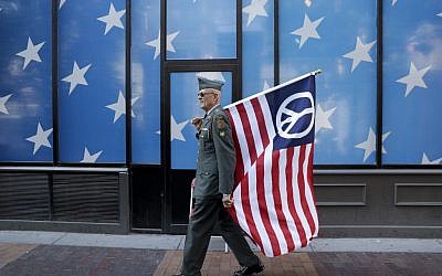 A protester carrying a peace flag walks in downtown Cleveland, Sunday, July 17, 2016, in preparation for the Republican National Convention. (AP Photo/Patrick Semansky)