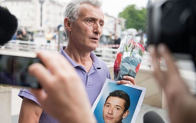 The father of a victim shows a picture of his son near the Olympia shopping center where a shooting took place leaving nine people dead the day before on Saturday, July 23, 2016 in Munich, Germany. (AP /Sebatian Widmann)