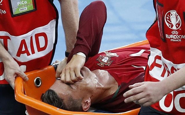 Portugal's Cristiano Ronaldo covers his face as he is stretchered off the pitch after suffering an injury during the Euro 2016 final soccer match between Portugal and France at the Stade de France in Saint-Denis, north of Paris, Sunday, July 10, 2016. (AP Photo/Michael Sohn)