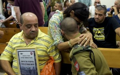 IDF soldier Elior Azaria, who is on trial for shooting and killing a disarmed Palestinian attacker, is embraced by a supporter in Jaffa Military Court on July 5, 2016 (Photo by Flash90)
