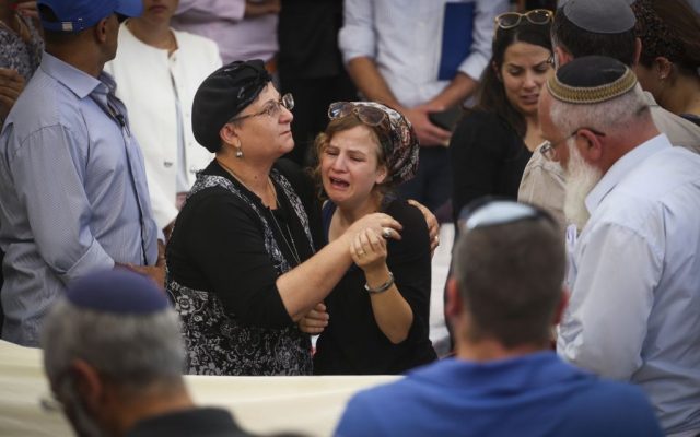 Friends and family mourn near the body of terror victim Rabbi Miki Mark during his funeral service at the Otniel yeshiva on July 3, 2016. (Hadas Parush/Flash90)