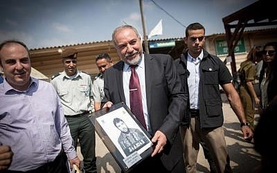 Defense Minister Avigdor Liberman holds up a picture of himself as a new army recruit at an IDF induction ceremony at the Tel Hashomer army base outside Tel Aviv on July 25, 2016. (Miriam Alster/Flash90)