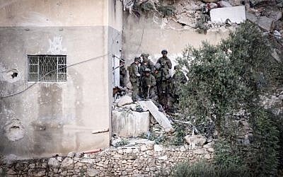 Israeli forces check the body of Palestinian Hamas fighter Mohammad al-Fakih, who murdered Rabbi Miki Mark in a terror attack a few weeks ago, and was killed during a raid in the West Bank village of Surif, near Hebron, July 27, 2016. (Wisam Hashlamoun/FLASH90)