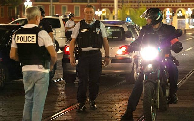 Police officers seal off the area of an attack after a truck drove on to the sidewalk and plowed through a crowd of revelers who'd gathered to watch the fireworks in the French resort city of Nice, southern France, Friday, July 15, 2016. (AP Photo/Ciaran Fahey)