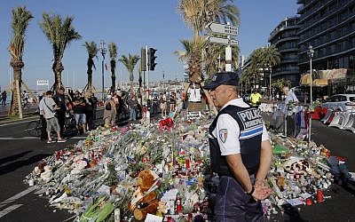 A police officer watches people gathering around a floral tribute for the victims killed during a deadly attack in Nice, southern France, Sunday, July 17, 2016. (AP/Laurent Cipriani)