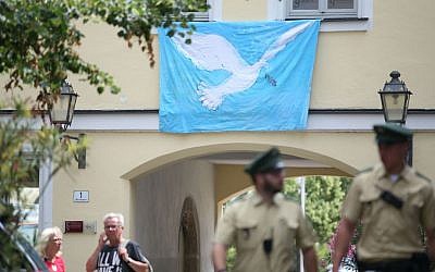 Police officers walk past a wall with a peace dove on a banner at the site of the attack in Ansbach, Germany, Tuesday, July 26, 2016. (Daniel Karmann/dpa via AP)