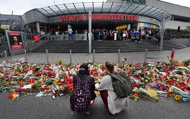 Flowers and candles have been placed in front of the main entrance of the Olympia-Einkaufszentrum shopping mall in Munich, Germany, Monday, July 25, 2016, after a rampage that left numerous people dead and injured. (Peter Kneffel/dpa via AP). Flowers and candles have been placed in front of the main entrance of the Olympia-Einkaufszentrum shopping mall in Munich, Germany, Monday, July 25, 2016, after a rampage that left numerous people dead and injured. (Peter Kneffel/dpa via AP).