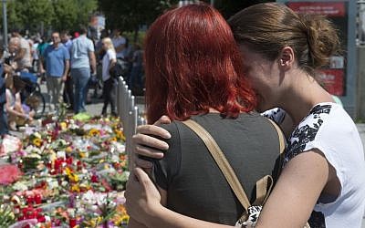 People mourn beside the Olympia shopping center where a shooting took place leaving nine people dead  in Munich, Germany, Sunday, July 24, 2016. (AP/Jens Meyer)