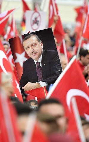 A picture of Turkish president Erdogan is framed by national flags during a demonstration in Cologne, Germany, Sunday, July 31, 2016. (AP Photo/Martin Meissner)