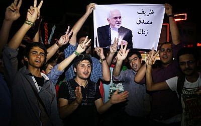 FILE -- In this July 14, 2015 file photo, young Iranian men cheer and show victory signs while holding a picture of Foreign Minister Mohammad Javad Zarif. (AP Photo/Ebrahim Noroozi, File)