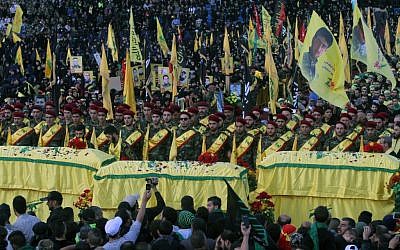 In this Tuesday, Oct. 27, 2015 file photo, relatives and comrades pray as they surround the Hezbollah flag-draped coffins of Shiite fighters who were killed in Syria, during a rally to mark the 13th day of the Shiite mourning period of Muharram, in Nabatiyeh, Lebanon. (AP Photo/Mohammed Zaatari, File)