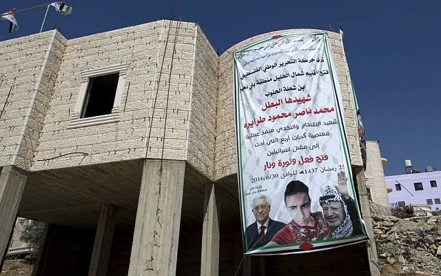 A banner with pictures of the late Palestinian leader Yasser Arafat, President Mahmoud Abbas and killer Mohammed Tarayrah, July 9, 2016 (AP Photo/Nasser Nasser)
