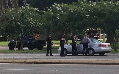 Authorities talk to the driver of a car near where several officers were shot while on duty, less than a mile from police headquarters, Sunday, July 17, 2016, in Baton Rouge, Louisiana. (AP Photo/Mike Kunzelman)