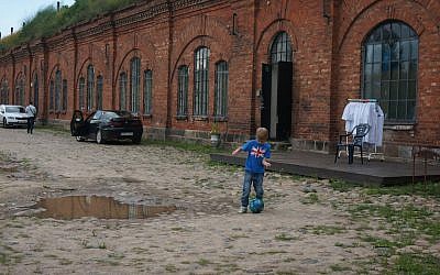 A boy playing soccer at the entrance to the former concentration camp known as the Seventh Fort in Kaunas, Lithuania, July 12, 2016. (Cnaan Liphshiz)